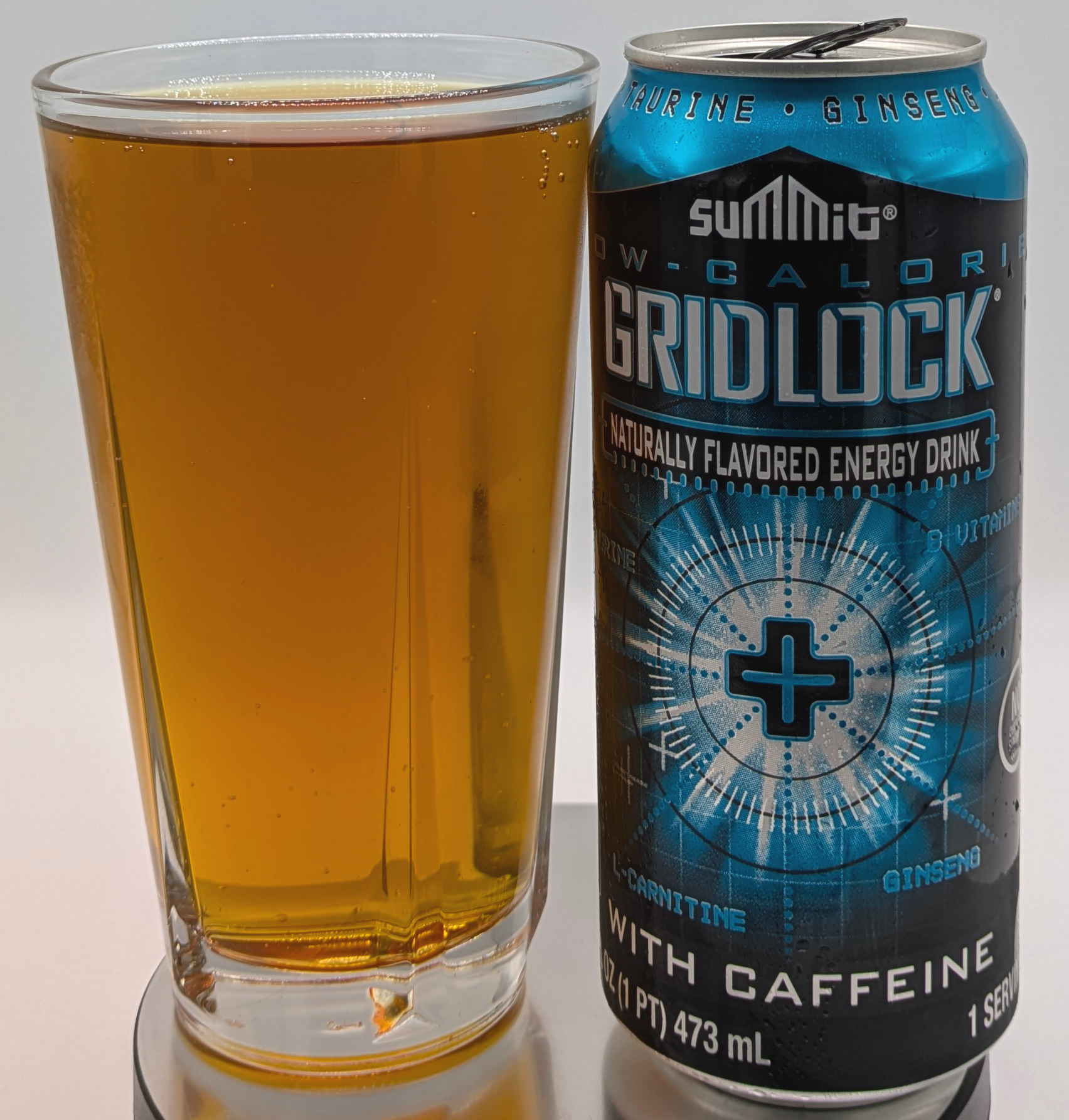 A can of Summit Low Calorie Gridlock next to a cup containing the liquid. The liquid is amber.